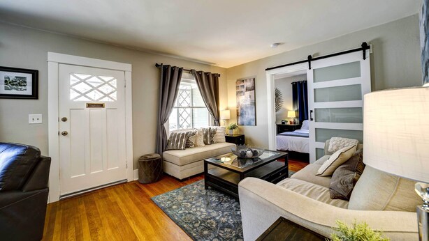 A living room with a sofa, a coffee table, a lamp, and a sliding door. - Historic Prescott Home w/ Yard & Fire Pit! (Prescott)