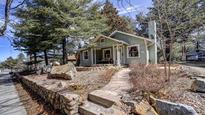 A single-story house with a stone retaining wall, a porch, and a driveway leading to the front door. - Historic Prescott Home w/ Yard & Fire Pit! (Prescott)