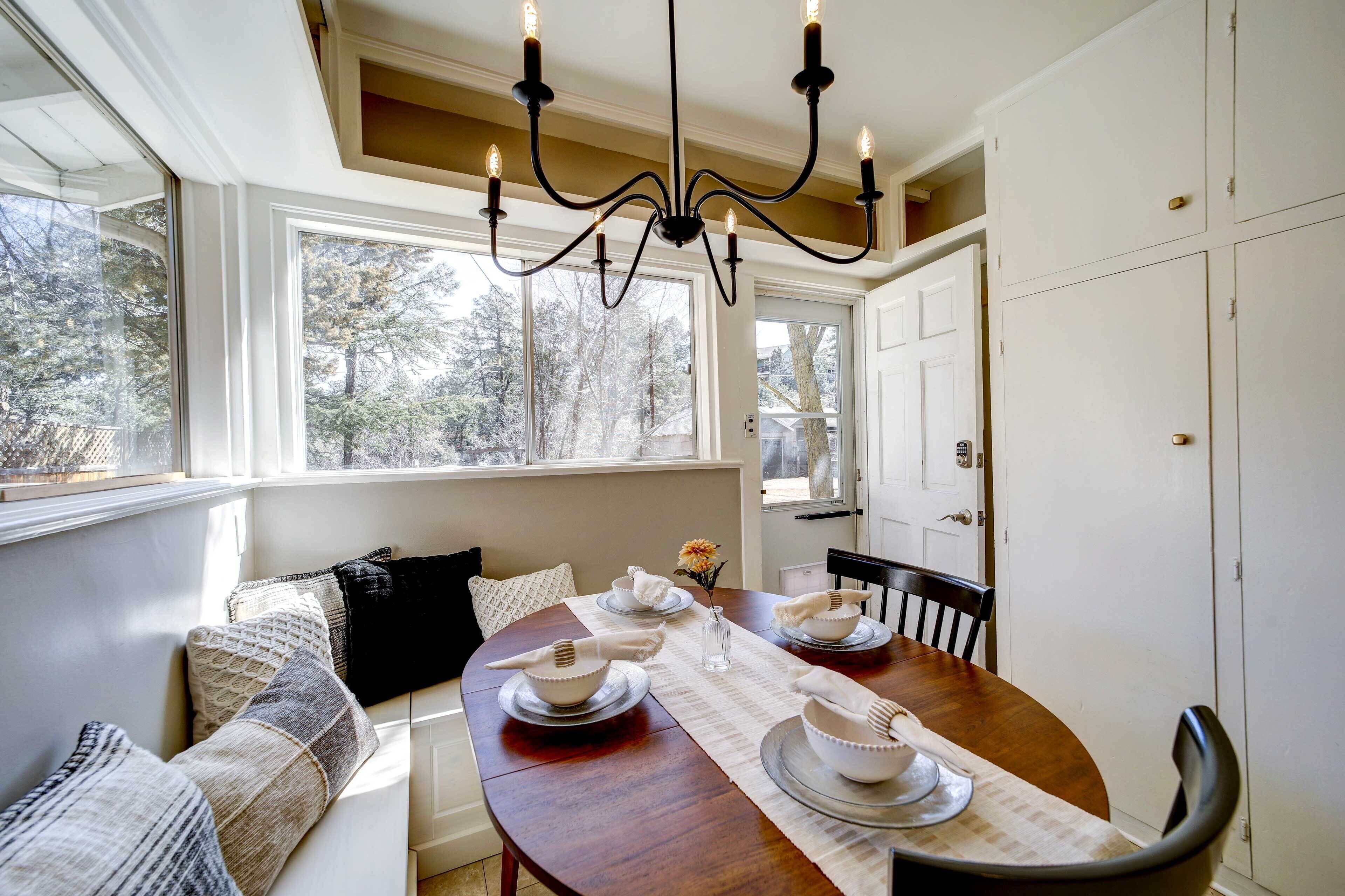 A dining area with a wooden table, white plates, and a chandelier.