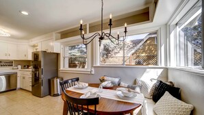 A kitchen with a dining table set for four, a chandelier, and a view of the backyard through large windows. - Historic Prescott Home w/ Yard & Fire Pit! (Prescott)