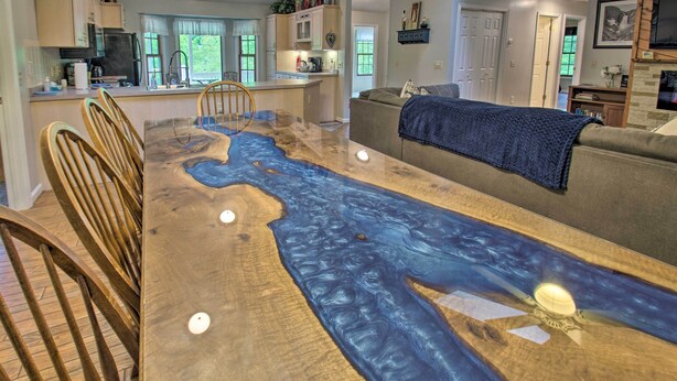 Een eettafel met een ontwerp dat doet denken aan een rivier, een bank en een televisie in een woonruimte.