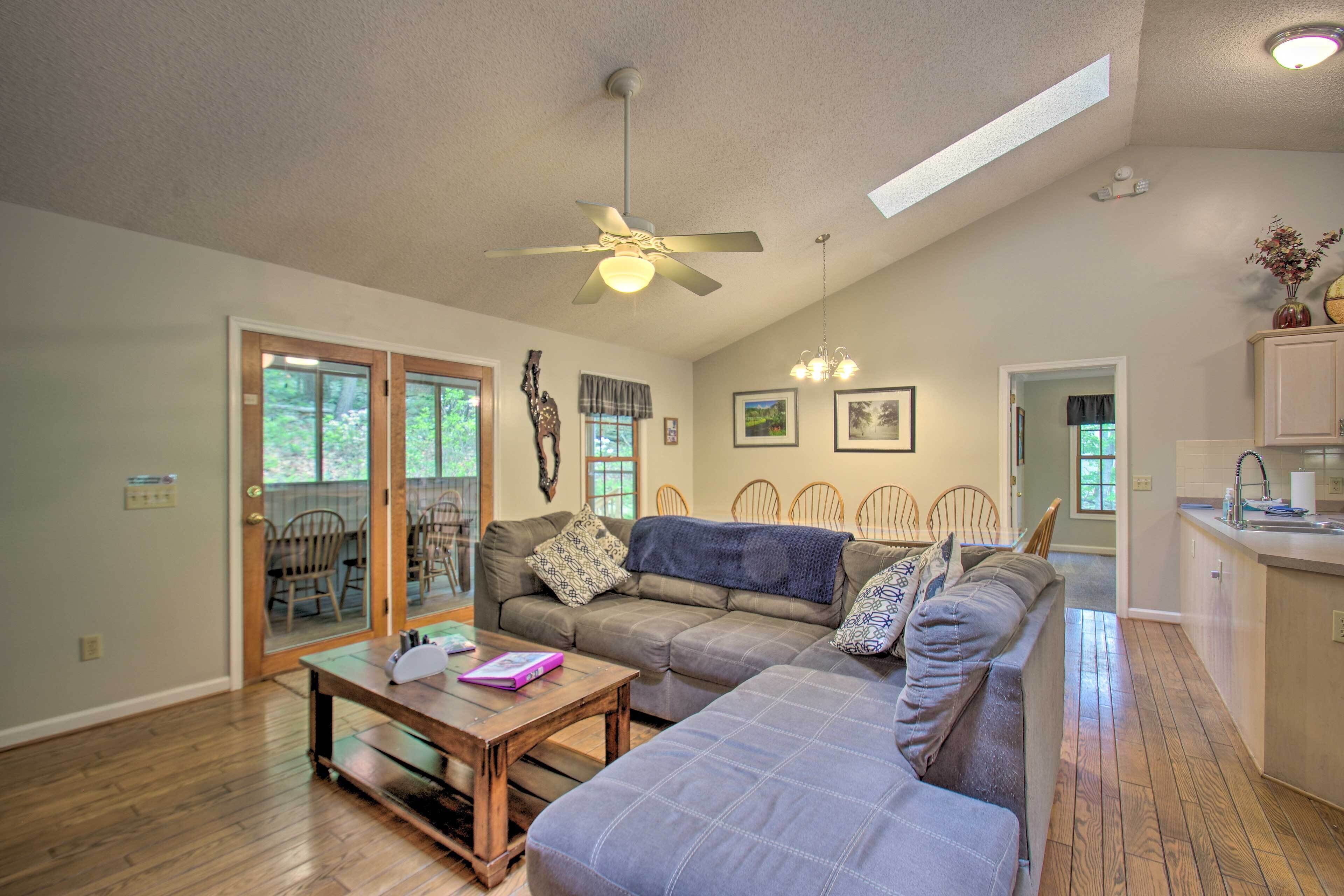 A spacious living room with a ceiling fan, a sofa, a coffee table, and a dining area with chairs.