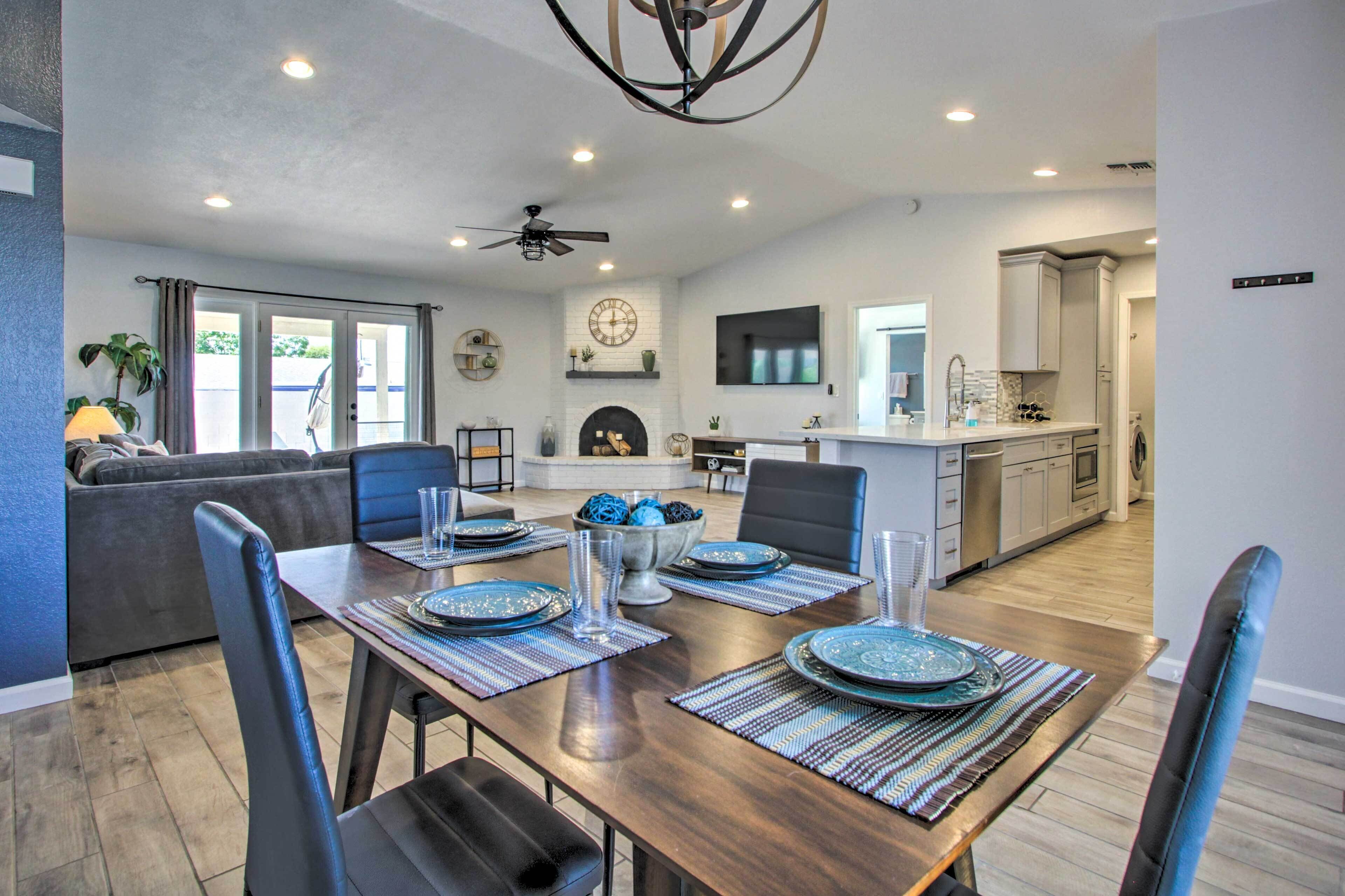 A modern dining area with a wooden table set for four, surrounded by dark leather chairs.