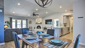 A modern dining area with a wooden table set for four, surrounded by dark leather chairs.