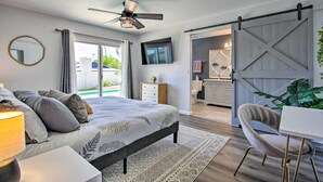 A bedroom with a bed, a desk, a chair, a TV, and a sliding barn door.