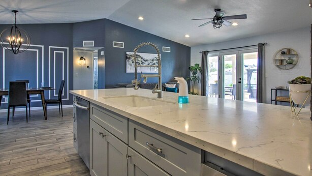 A modern kitchen with a large island, built-in appliances, and a dining area with a table and chairs.