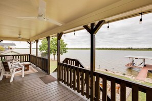 A wooden deck with outdoor furniture, a railing, and a view of a body of water.
