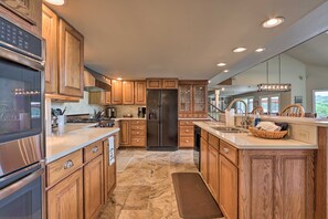 A modern kitchen with wooden cabinets, stainless steel appliances, and a stone tile floor. - Lakefront Haven: Family-friendly Sunrise Beach Gem (Sunrise Beach)