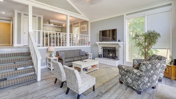A spacious living area with a staircase, a fireplace, and a television.