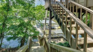 A wooden staircase leading to a deck over water, surrounded by trees.