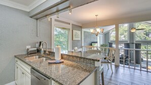 A kitchen with granite countertops, a dishwasher, and a dining area with a table and chairs.