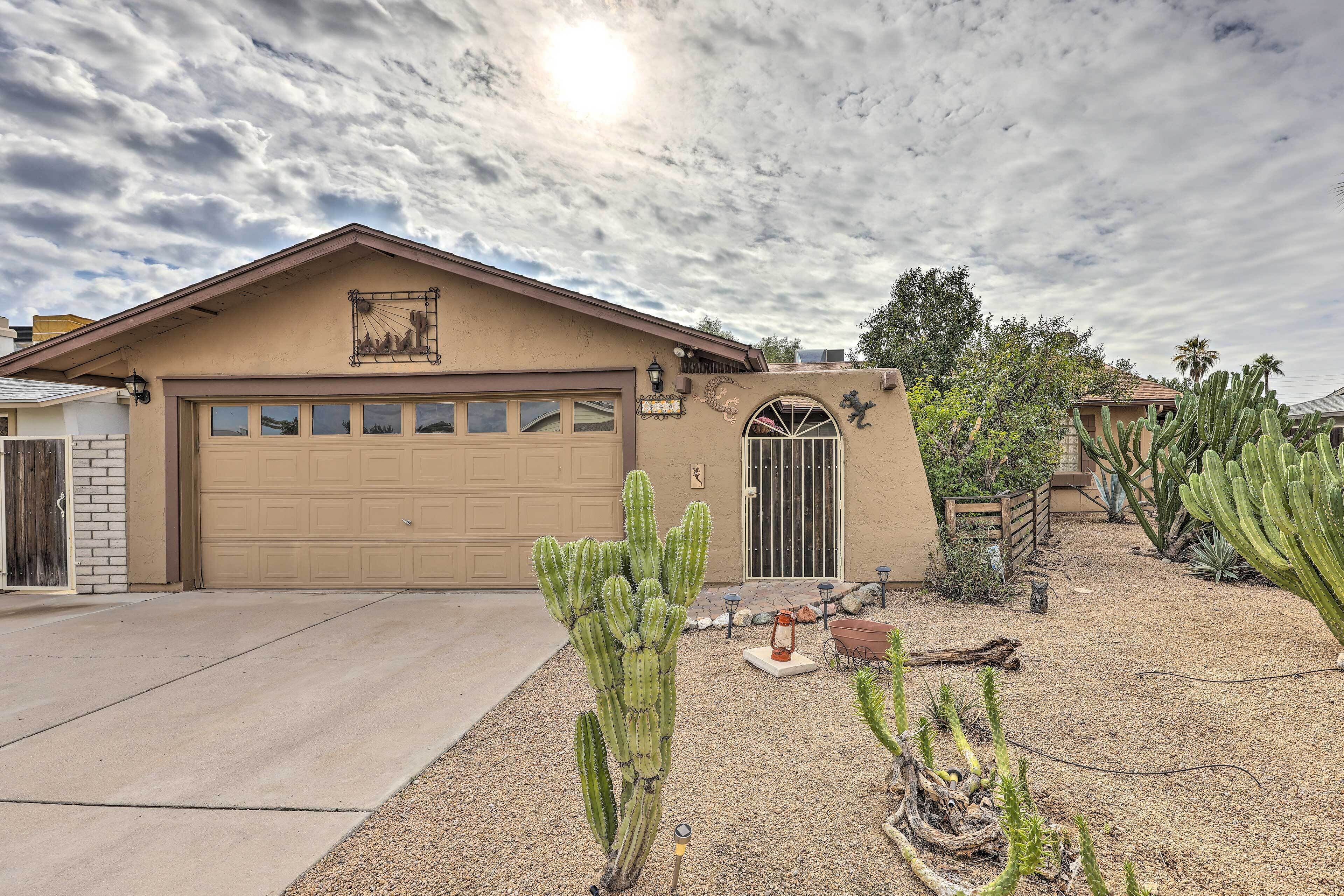 A single-story house with a garage, surrounded by cacti and desert plants.