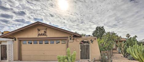 A single-story house with a garage, surrounded by cacti and desert plants.