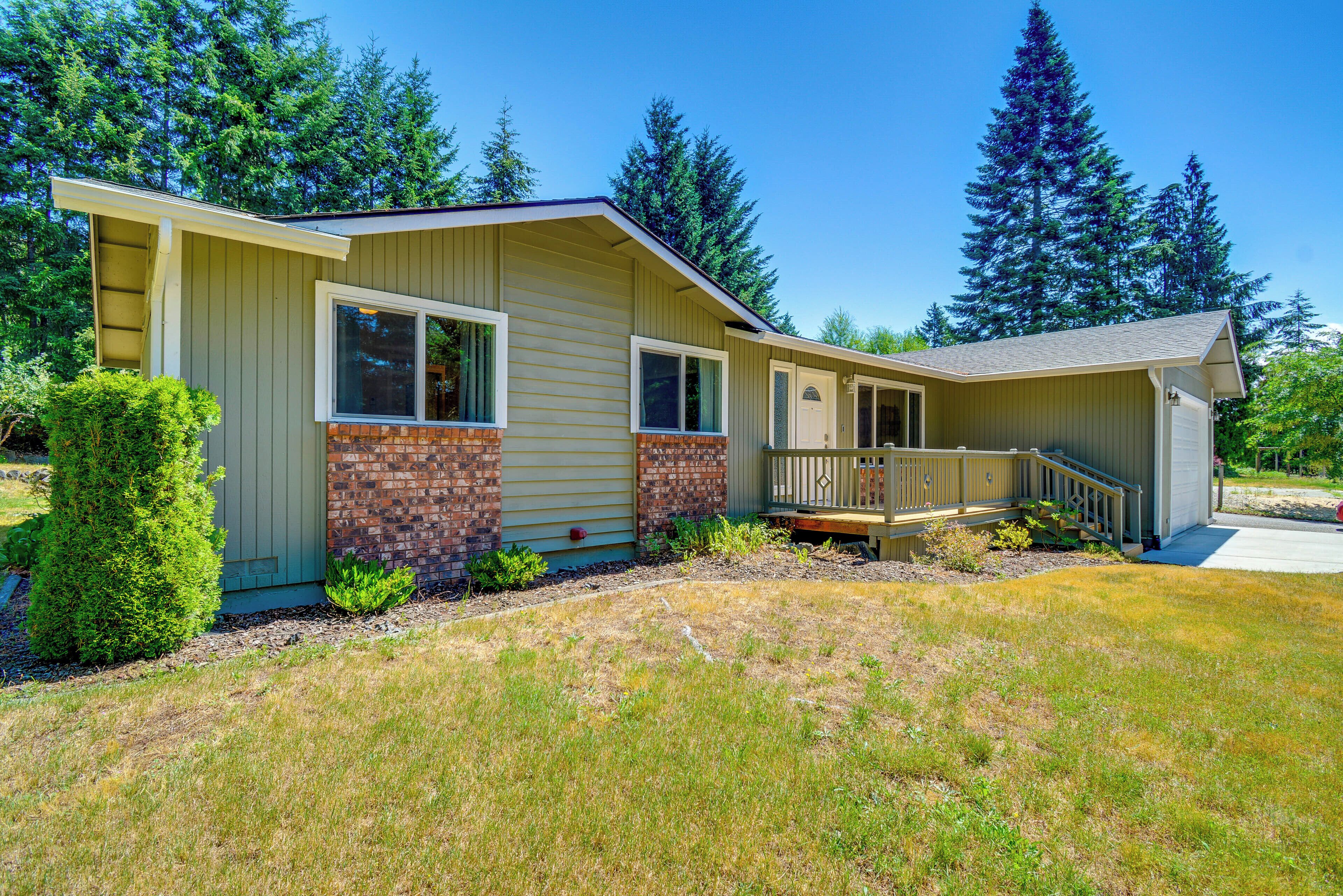 A single-story house with a front porch, a small deck, and a brick foundation.
