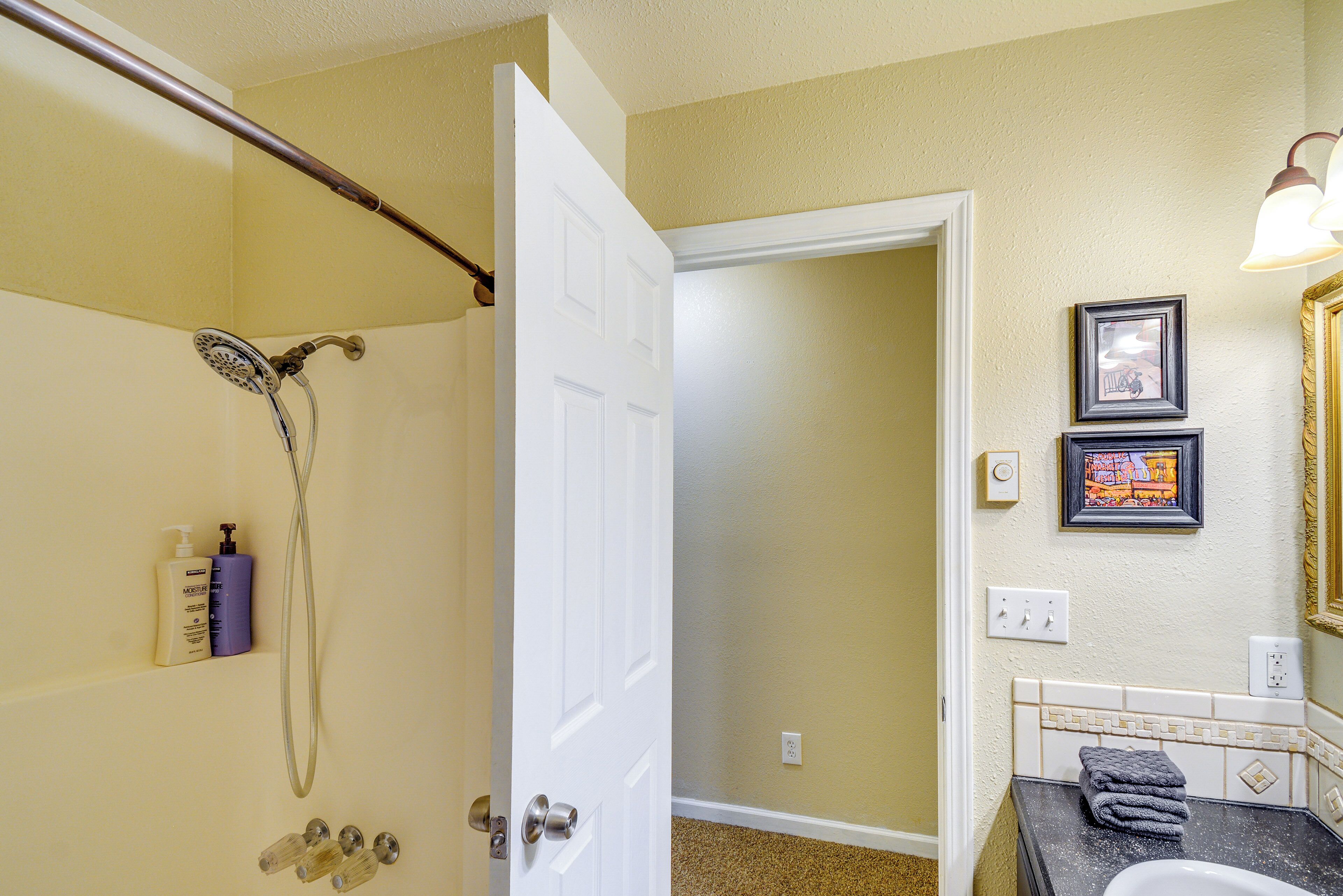 A bathroom with a shower, a toilet, and a sink. There are toiletries on the wall and a towel on the sink.