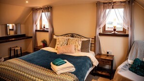 Un dormitorio con cama, mesitas de noche, un espejo y una ventana con cortinas.