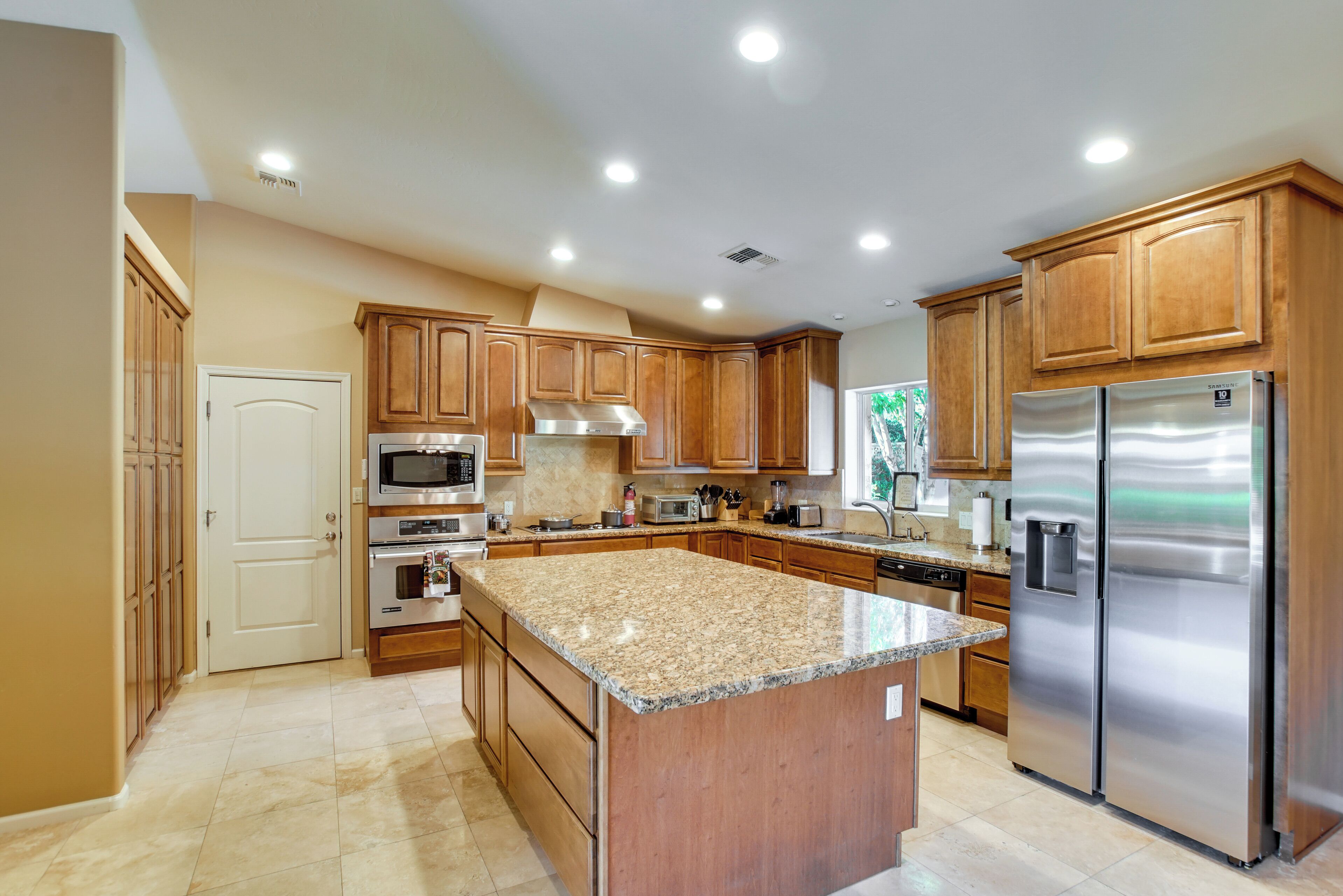 A modern kitchen with wooden cabinets, stainless steel appliances, and a granite countertop.