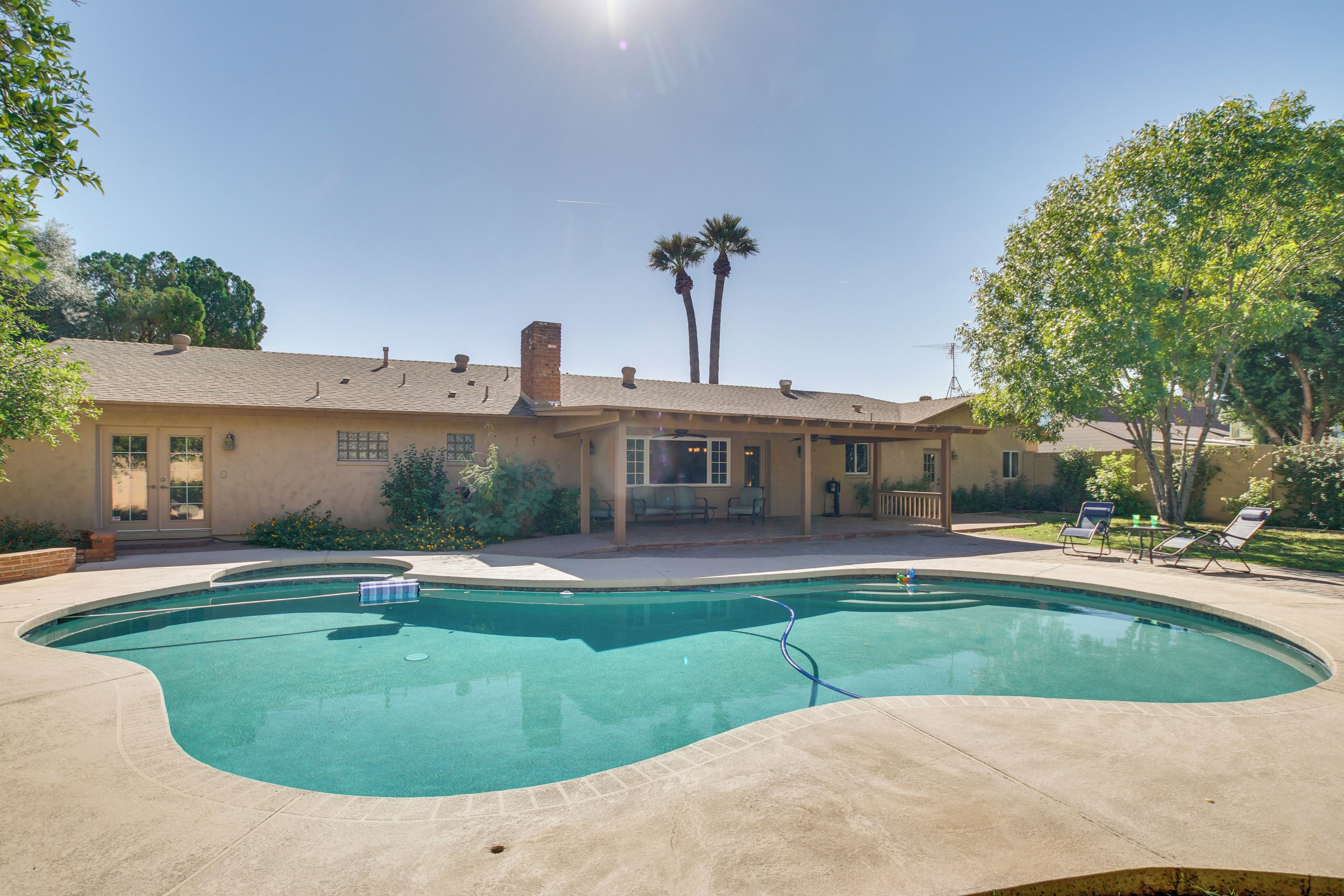 Una casa con piscina, patio y jardín.