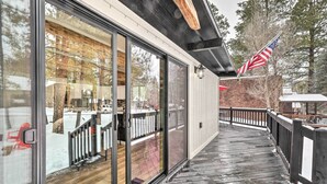 Een houten terras met glazen deuren die leiden naar een overdekt buitengebied, een bakstenen muur en een Amerikaanse vlag.