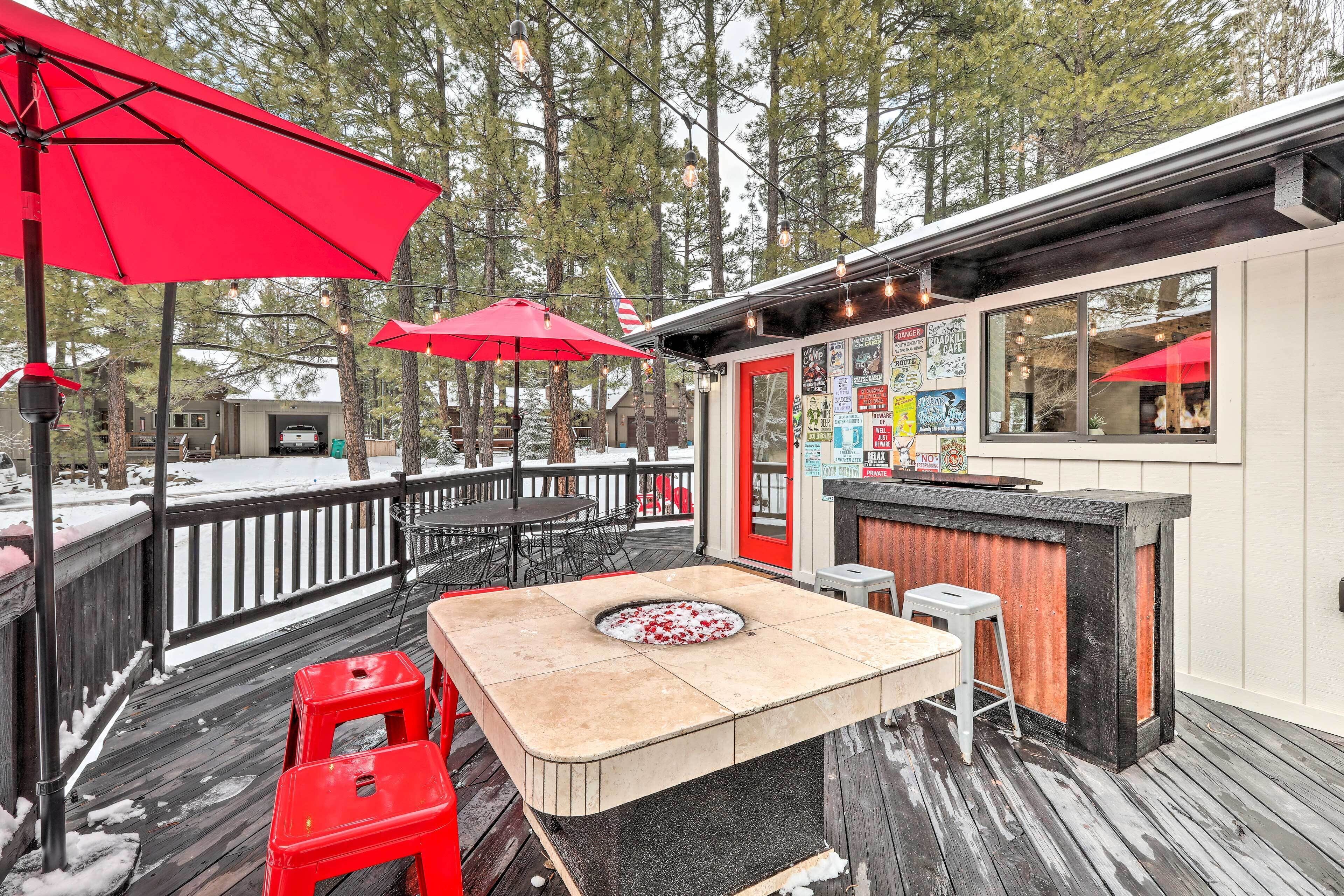 Une terrasse dotée d’un bar, de parasols rouges et d’un sol en bois.