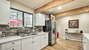 Een moderne keuken met witte kastjes, een roestvrijstalen koelkast, een houten plafond en een Route 66 bord aan de muur.