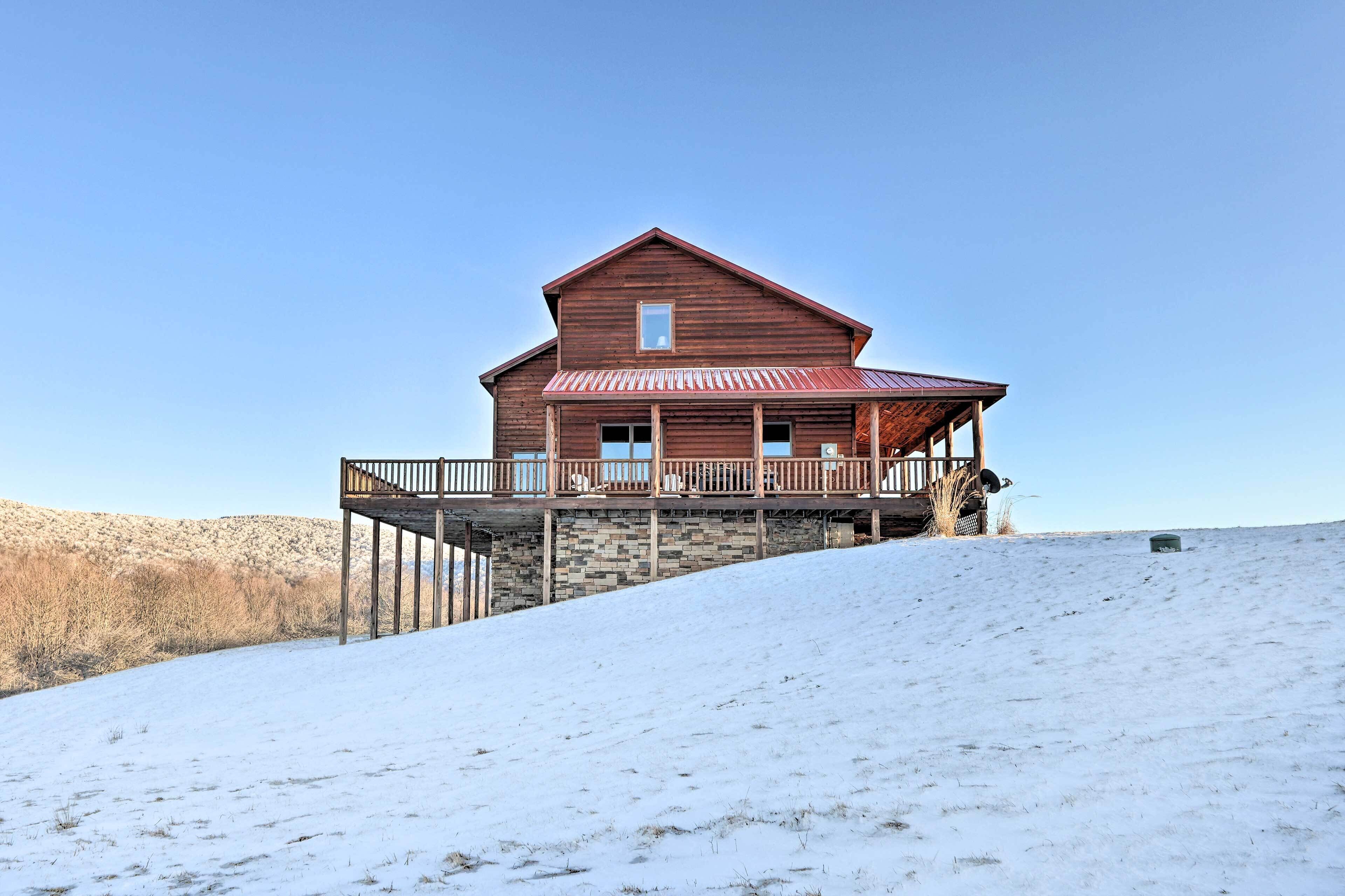 Una cabaña de madera con balcón, ubicada en una colina nevada.