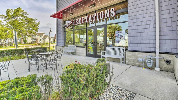 A storefront with the sign "Sweet Temptations" and outdoor seating with tables and chairs. - Grand Haven Condo w/ Patio < 1 Mi to Downtown (Grand Haven)