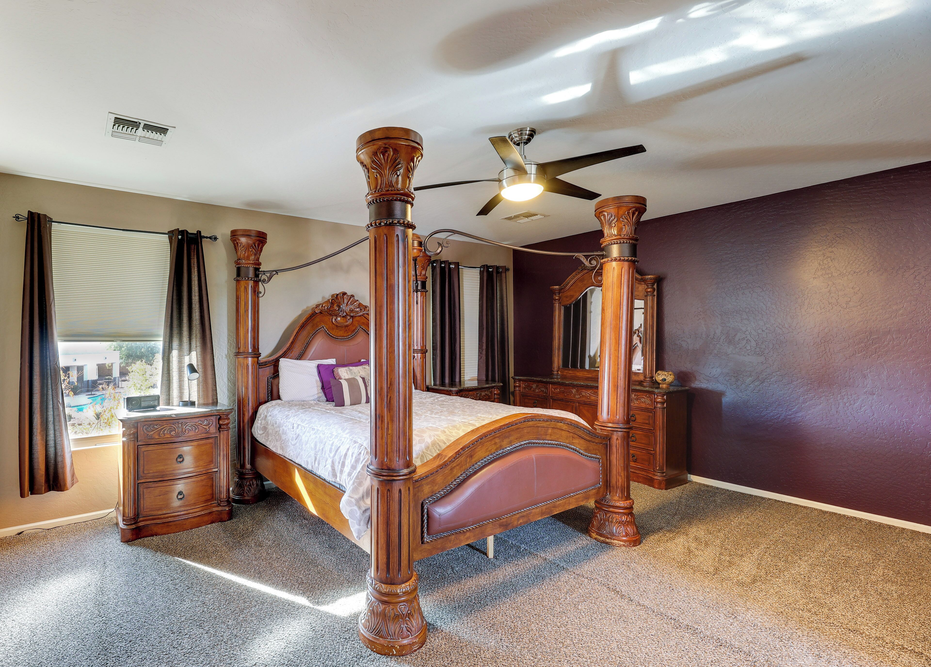 Ein Raum mit Himmelsbett, Deckenventilator, Nachttisch und Kommode, mit Blick.