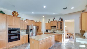 A spacious kitchen with wooden cabinets, a stainless steel refrigerator, an oven, and a large island.