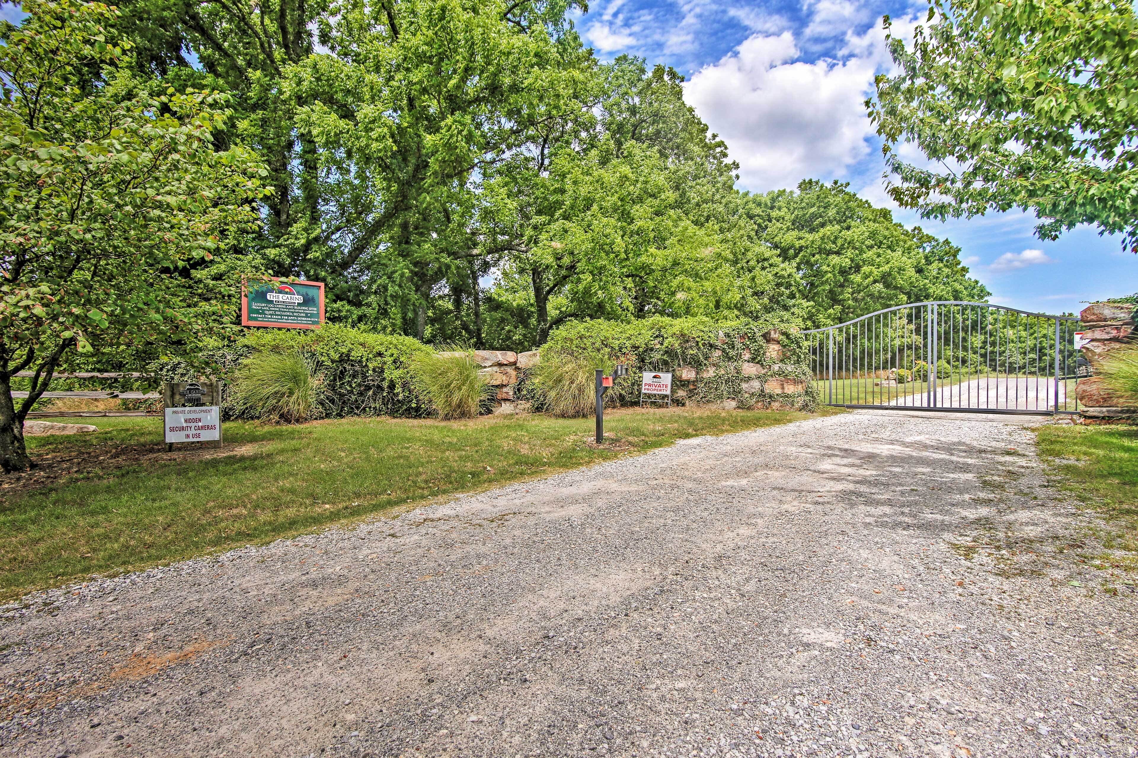 A gravel driveway leading to a gated entrance with a sign indicating a private area.