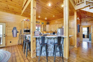 Une cabane en bois avec un bar en forme d’îlot en pierre, des armoires en bois et un panneau d’accueil en forme d’ours.
