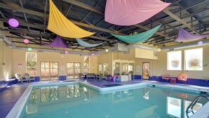 Piscina interior con vista despejada al techo, ventanas y asientos junto a la piscina.