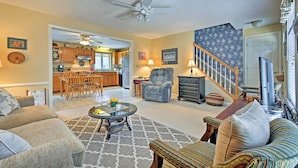 A living room with a sofa, armchair, and coffee table. There is a staircase leading to another level. - Charming Owls Head Retreat: 2 Mi to Rockland Coast (Owls Head)