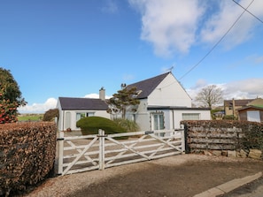 A white two-story house with a gated driveway, a chimney, and a well-maintained lawn. - Llwyn Celyn (Pwllheli)