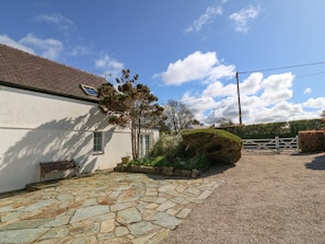 A stone-paved courtyard with a bench, a tree, and a hedge. - Llwyn Celyn (Pwllheli)