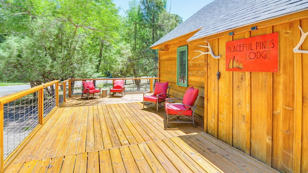 A wooden deck with red chairs and a sign reading "Peaceful Pines Lodge". - Family-friendly House: Fish, Hike, Bike & More! (South Fork)