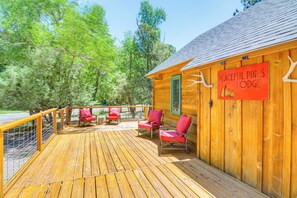 A wooden deck with red chairs and a sign reading "Peaceful Pines Lodge". - Family-friendly House: Fish, Hike, Bike & More! (South Fork)