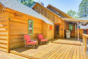 A wooden cabin with a porch, two red chairs, and a small heater.