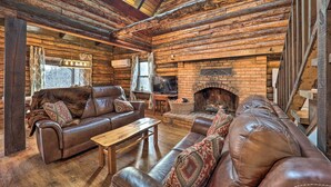 A rustic log cabin interior with leather sofas, a wooden table, a fireplace, and a television. - Relaxing Retreat w/ Private Dock on Claytor Lake! (Dublin)