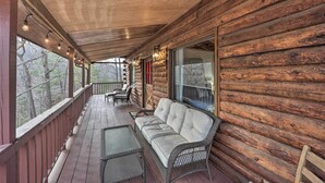 A log cabin with a porch, wicker furniture, and a view of trees. - Relaxing Retreat w/ Private Dock on Claytor Lake! (Dublin)