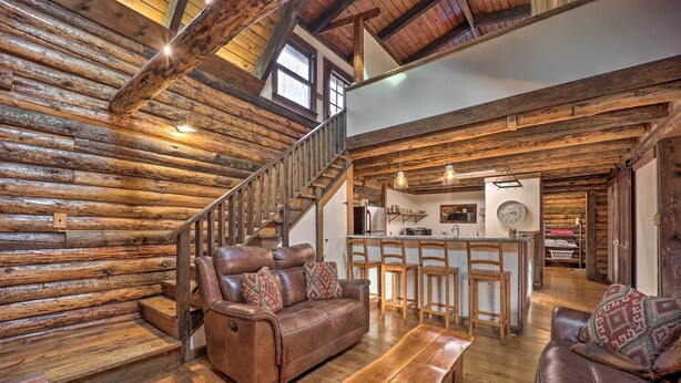 A log cabin interior with a leather sofa, wooden bench, and a staircase leading to a kitchen area. - Relaxing Retreat w/ Private Dock on Claytor Lake! (Dublin)