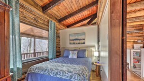 A log cabin bedroom with a bed, wooden walls, a window, and a painting on the wall. - Relaxing Retreat w/ Private Dock on Claytor Lake! (Dublin)