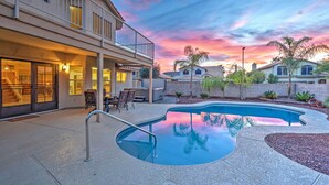 A residential property with a swimming pool, a covered patio, and a two-story house with a balcony. - Hot Tub & Pool: Stunning Goodyear Home Near Lakes (Goodyear)