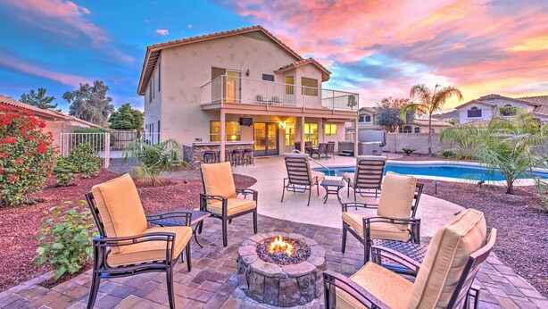 A two-story house with a patio area featuring outdoor furniture and a fire pit. - Hot Tub & Pool: Stunning Goodyear Home Near Lakes (Goodyear)