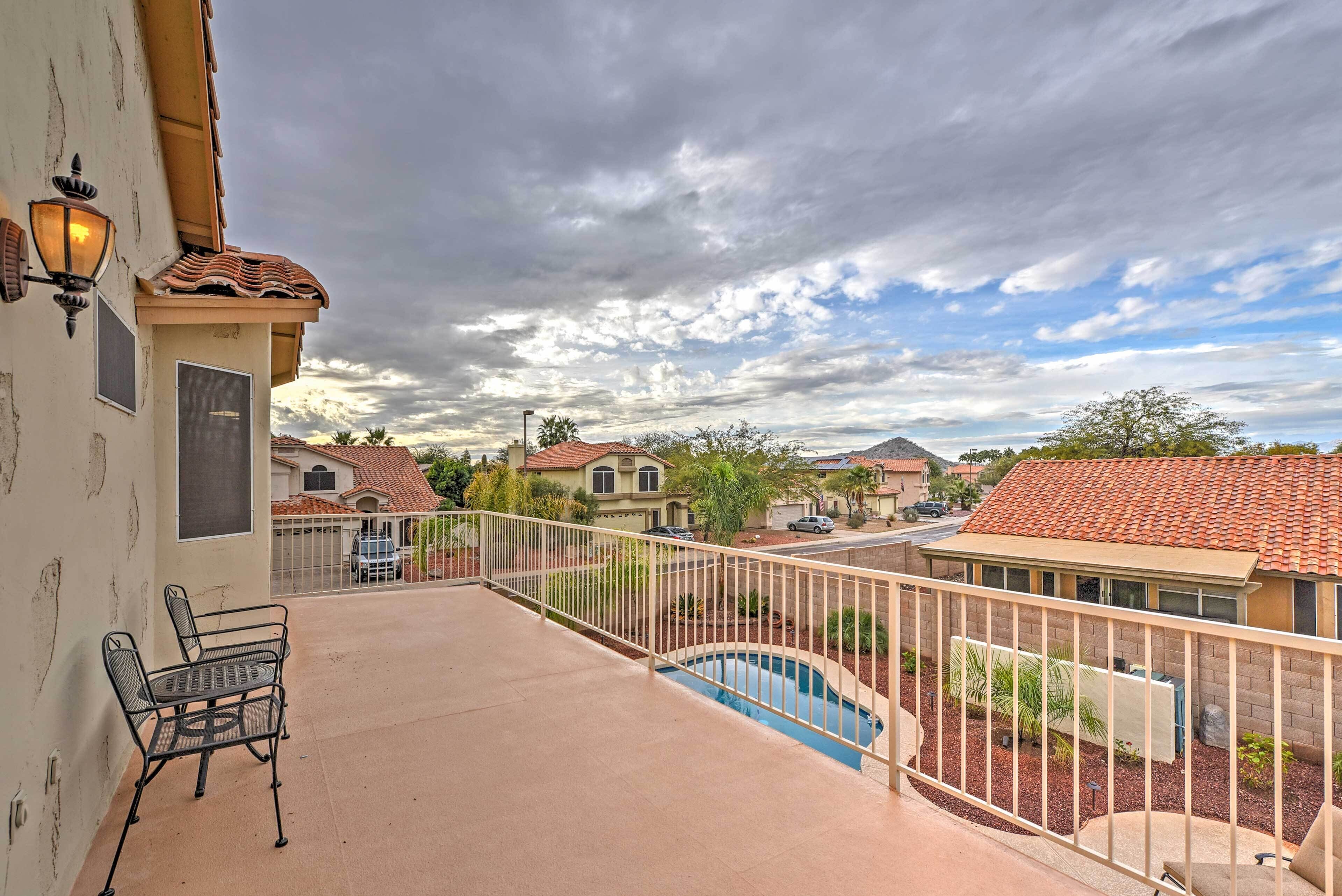 A balcony with a metal chair, a small pool, and a view of neighboring houses.