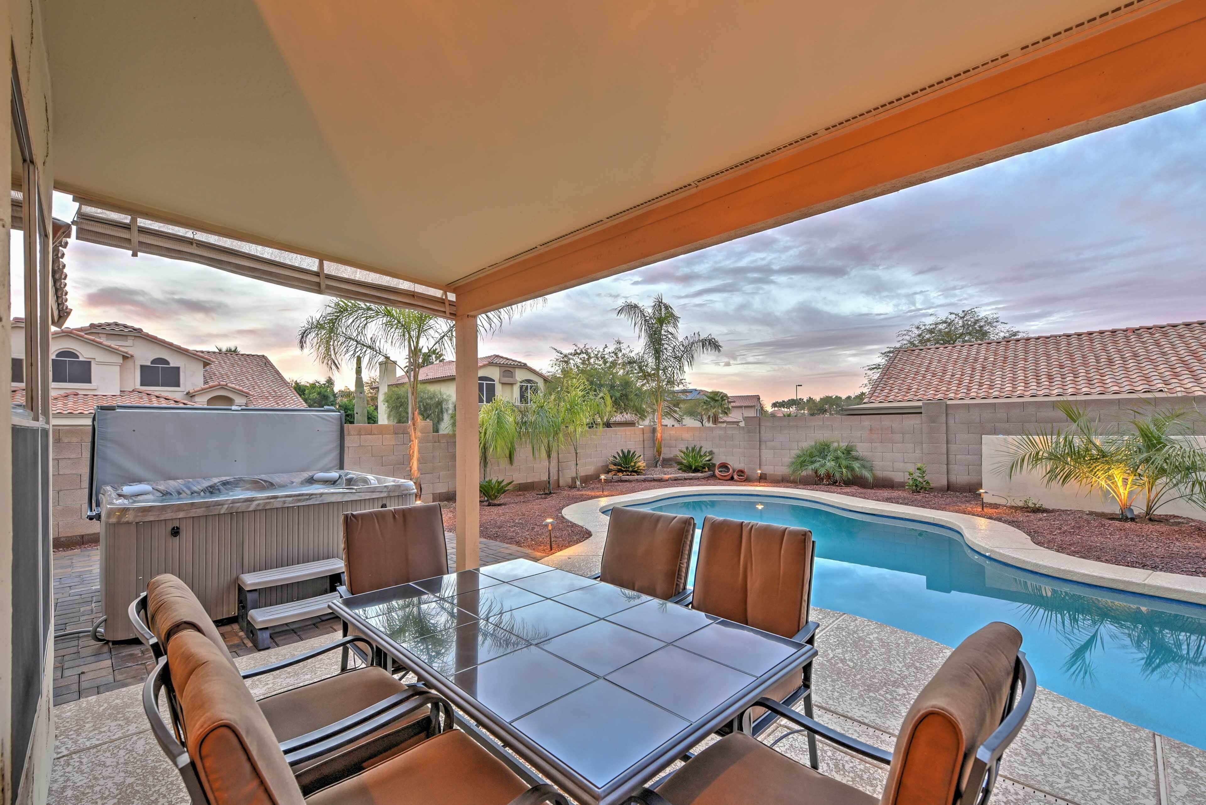 A covered patio area with a hot tub, a pool, and outdoor seating.