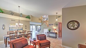 A spacious living area with a dining table, sofas, and a staircase leading to an upper level. - Hot Tub & Pool: Stunning Goodyear Home Near Lakes (Goodyear)