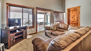 A living room with a leather sofa, wooden entertainment unit, and large windows. - Cabin w/ Gradual Slope to Sandy Bottom Swimming! (Siren)