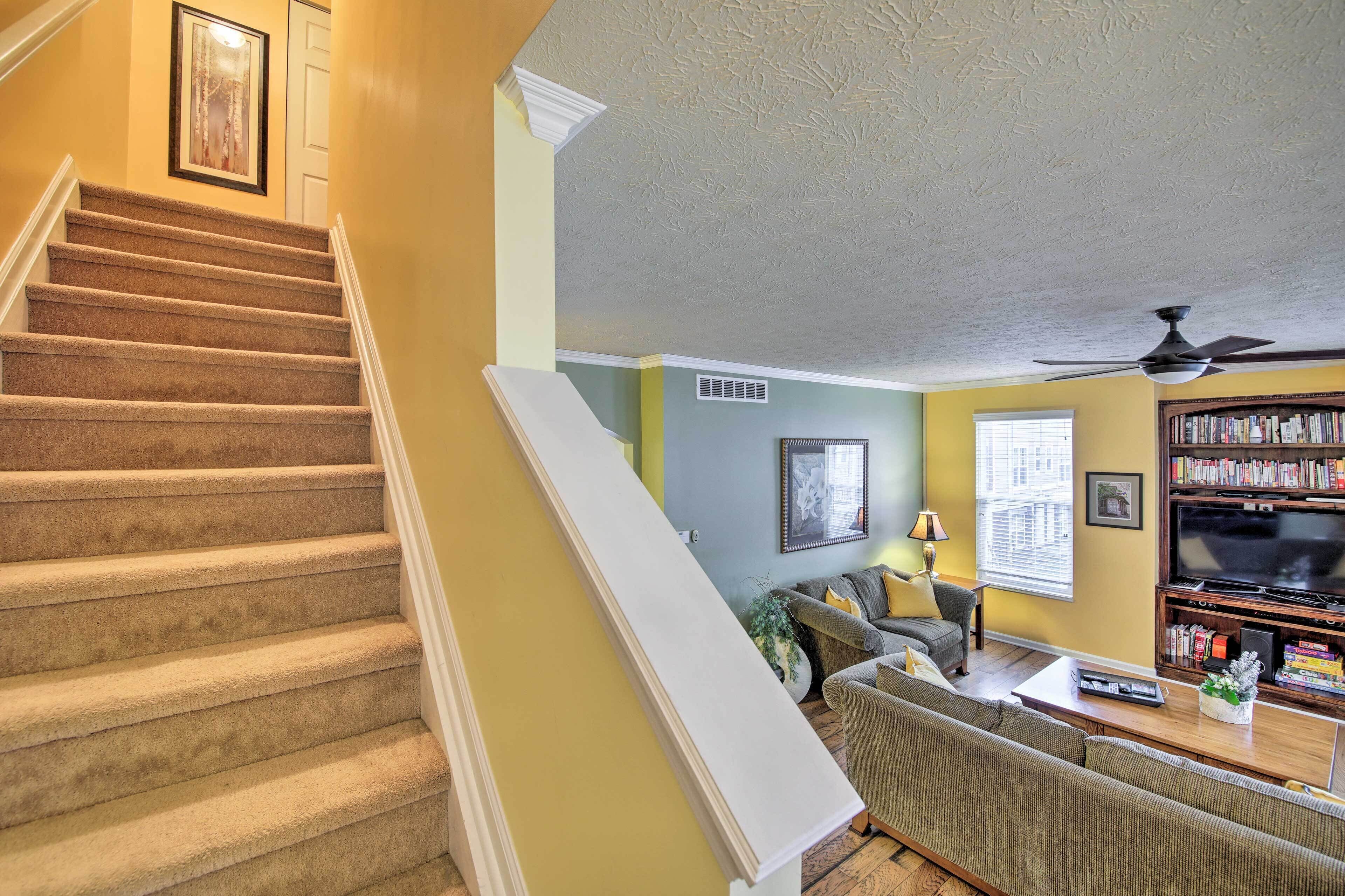 A staircase leading to a living room with a sofa, television, and bookshelves.