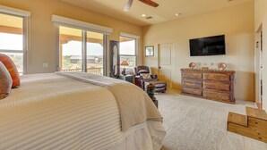 A bedroom with a large bed, a ceiling fan, a dresser, a TV, and a view through the door. - 'the Hideaway' - Santa Fe-style Home in Rio Verde! (Rio Verde)